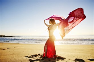Caucasian belly dancer holding scarf on beach
