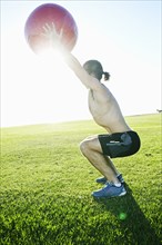 Caucasian man exercising with fitness ball in sunny field