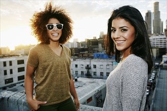 Portrait of smiling Hispanic women on urban rooftop at sunset
