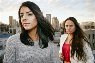 Portrait of serious Hispanic women on urban rooftop at sunset