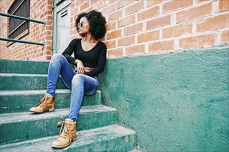 Black woman sitting on staircase outdoors