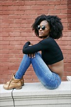 Portrait of Black woman sitting on ledge outdoors