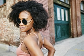 Black woman smiling near corner of brick building