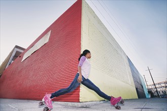 Black woman wearing roller skates gliding around corner