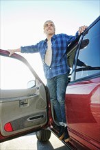 Caucasian man standing in car door