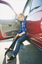 Caucasian man sitting in car holding skateboard wheel