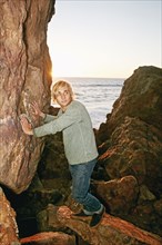 Caucasian man leaning on rocks at ocean