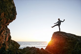 Caucasian man balancing on rock at ocean