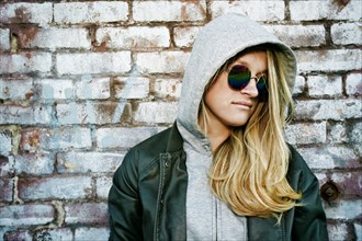 Caucasian woman wearing sunglasses near brick wall