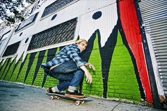 Caucasian man skateboarding on urban sidewalk