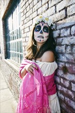 Mixed Race woman on sidewalk wearing skull face paint