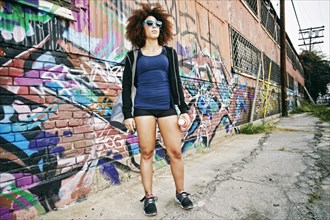 Hispanic woman standing near graffiti wall