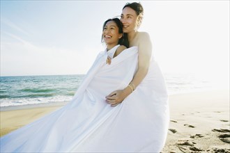 Women wrapped in sheet at beach