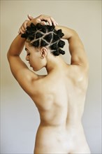 Rear view of naked Mixed Race woman with arms raised