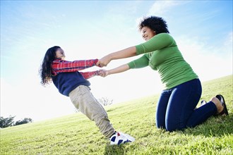 Mixed race mother and daughter playing in grass
