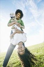 Smiling mixed race mother holding daughter upside-down