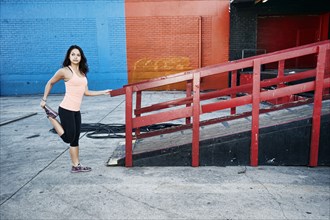 Mixed race woman stretching leg at loading dock