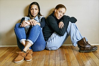 Serious mixed race women sitting on floor