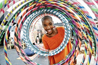 Portrait of smiling bald black woman behind hoops