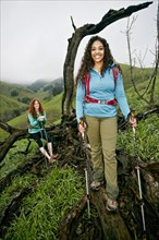 Smiling hiking women resting on a tree