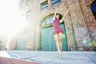 Sunbeams on mixed race woman dancing in city