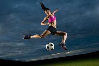 Japanese woman playing soccer at night