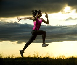 Mixed race woman running in field at night