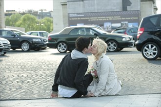 Caucasian man kissing girlfriend on busy street