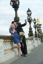 Caucasian couple taking self-portrait on bridge