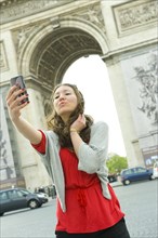Caucasian woman taking self-portrait near Arc de Triomphe