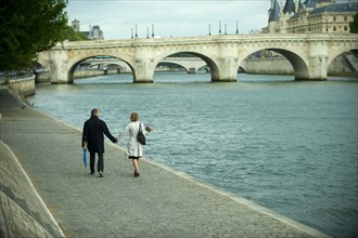 Caucasian couple holding hands and walking near river