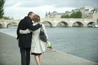 Caucasian couple kissing near city river