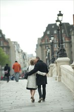 Caucasian couple kissing and walking on bridge