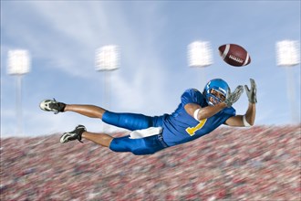 Mixed race football player jumping in mid-air catching football