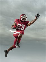 Black football player carrying football in mid-air
