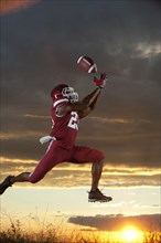 Black football player catching football player in mid-air