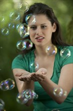 Caucasian woman trying to catch bubbles in her hands