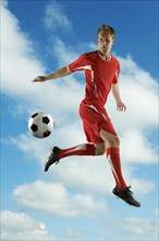 Soccer player jumping in mid-air kicking ball