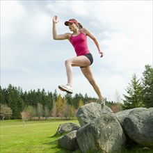 Mixed race teenager jumping from rock