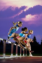 Runners jumping hurdles in race