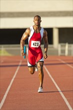 Black runner running on track in relay race