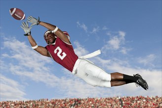 Black football player catching football in mid-air
