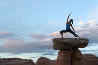 Caucasian woman practicing yoga on top of rock formation