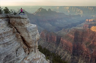 Caucasian woman practicing yoga on cliff near canyon
