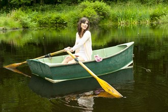 Caucasian woman rowing boat in pond