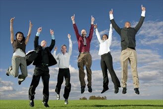 Business people jumping and cheering in field