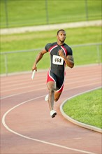 Black runner carrying baton in relay race