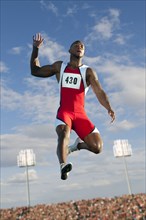 Black high jumper in mid-air at track & field event