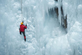 Caucasian man climbing ice wall