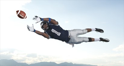 African American football player catching ball